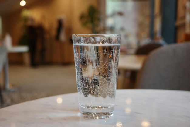 A glass of still water with bubbles on a cafe table close-up shot.