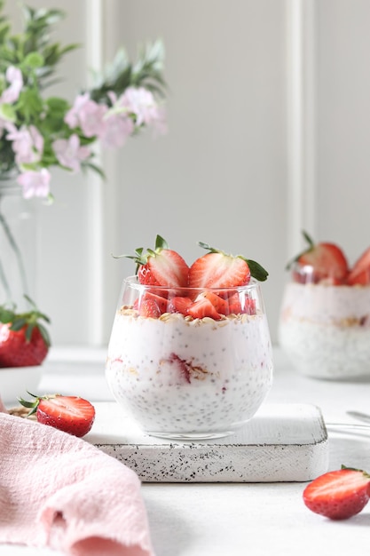 A glass of strawberry chia pudding with chia seeds in the background.