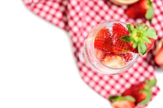 Glass of strawberry cocktail soda placed on a plaid tablecloth isolated on white background.