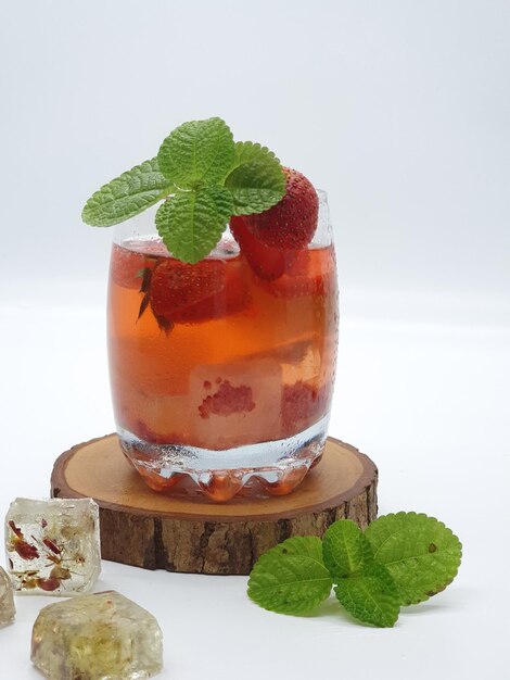 Foto un bicchiere di cocktail alla fragola con foglie di menta su una base di legno.