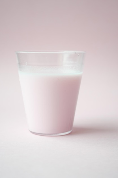 Glass of strawberry milk on pink background