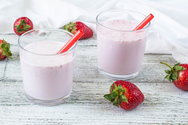 Glass of strawberry smoothie with straws on a wooden table