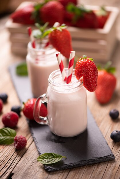 Glass of strawberry smoothie on wooden background cllose up