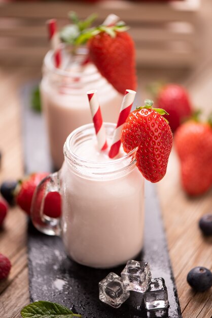 Glass of strawberry smoothie on wooden background cllose up