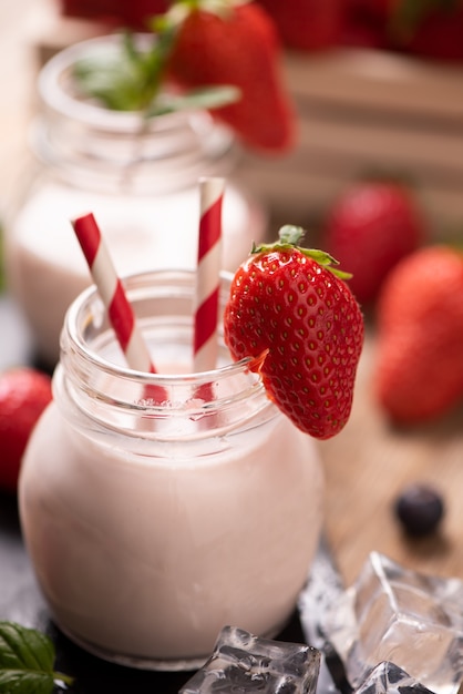 Glass of strawberry smoothie on wooden background cllose up