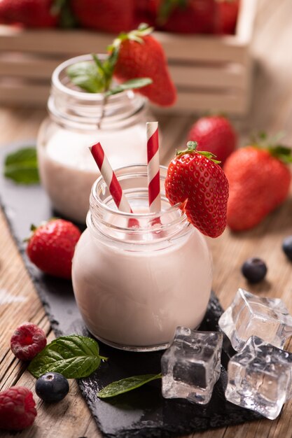 Glass of strawberry smoothie on wooden background cllose up