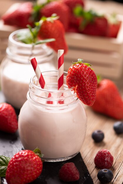 Glass of strawberry smoothie on wooden background cllose up