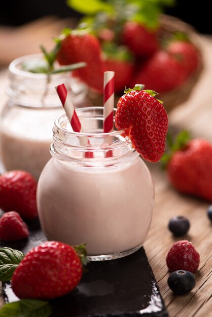 Glass of strawberry smoothie on wooden background cllose up