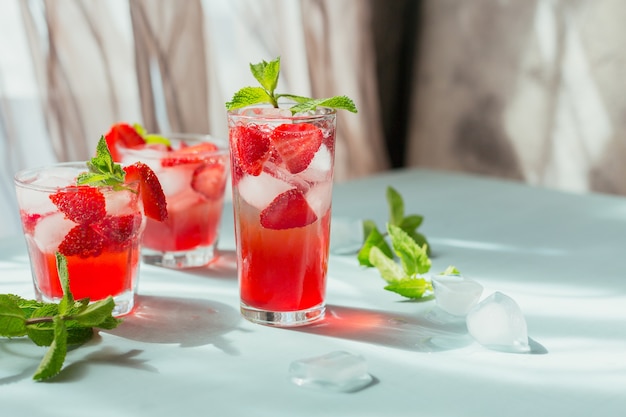 Glass of strawberry soda drink on light blue surface