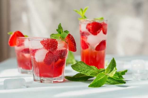 Glass of strawberry soda drink on light blue