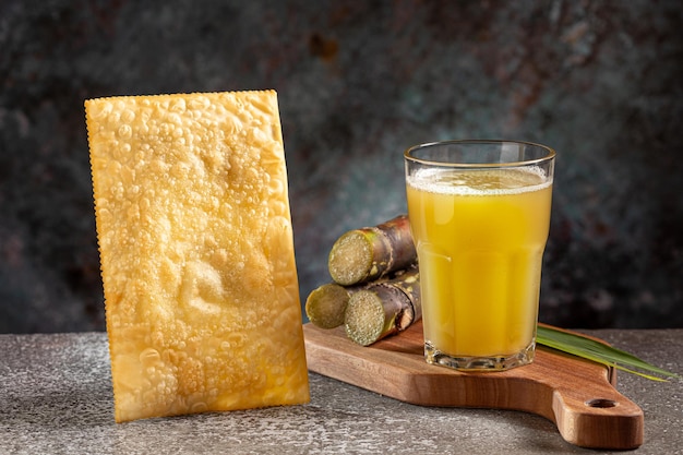 Foto un bicchiere di succo di canna da zucchero con pasticceria fritta uno spuntino tipico brasiliano