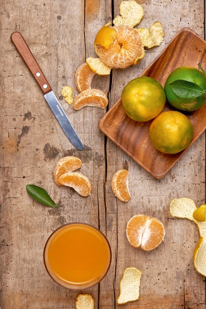 Glass of tangerine juice and fresh peeled fruits