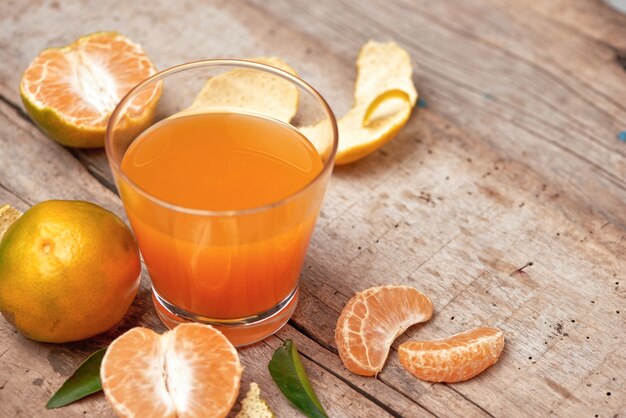 Glass of tangerine juice and fresh peeled fruits