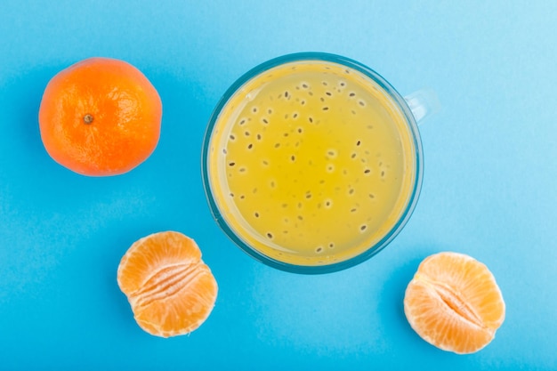 Photo glass of tangerine orange colored drink with basil seeds on a blue background. morninig, spring, healthy drink concept. top view,  close up, flat lay.