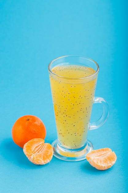 Glass of tangerine orange colored drink with basil seeds. Side view