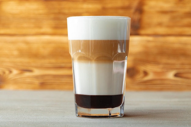 Glass of tasty aromatic latte on wooden background