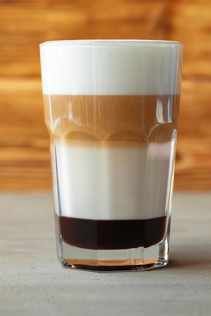 Glass of tasty aromatic latte on wooden background