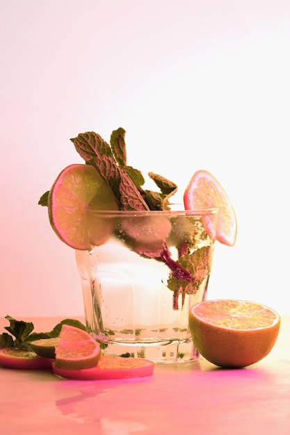 glass of tasty cocktail with orange and lemon on color background toning itrus summer drink closeup