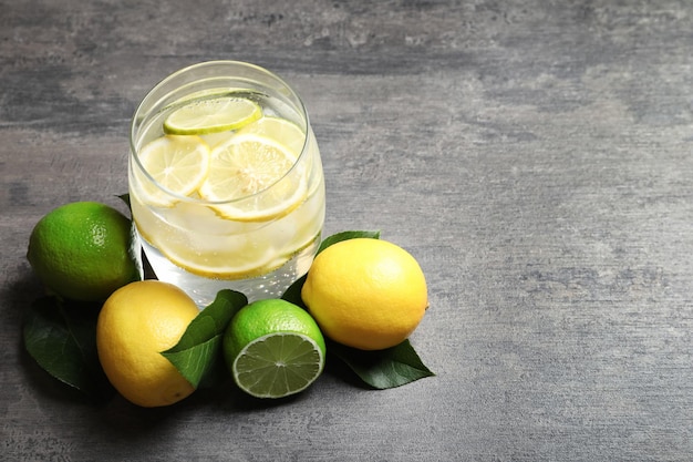 Glass of tasty lemonade with citrus fruits on grey table