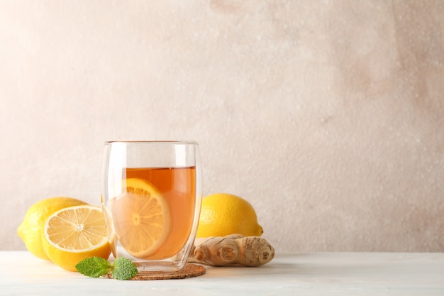 Foto bicchiere di tè con limone, menta, miele, mestolo e zenzero su legno, copia spazio