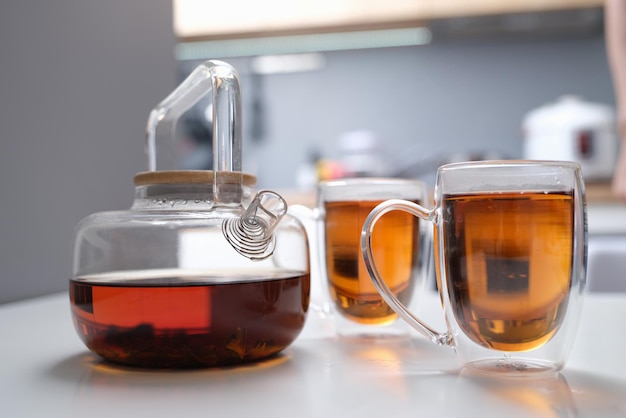 Glass teapot and transparent cups with tea on the table