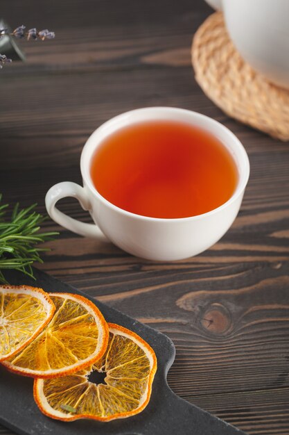 Glass teapot with cup of black tea on wooden table