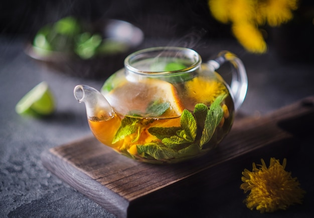 写真 フルーツハーブティーとガラスのティーポット。広告構成：オレンジ、ミント、シーバックソーン、ハーブ入りのお茶。