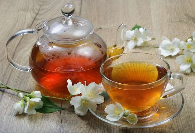 A glass teapot with a glass lid and a glass jar of tea.