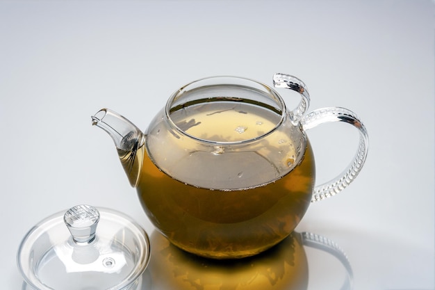 Glass teapot with green tea on white background