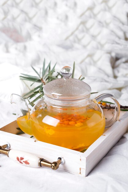 A glass teapot with sea buckthorn