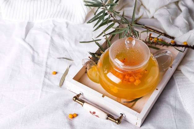 A glass teapot with sea buckthorn