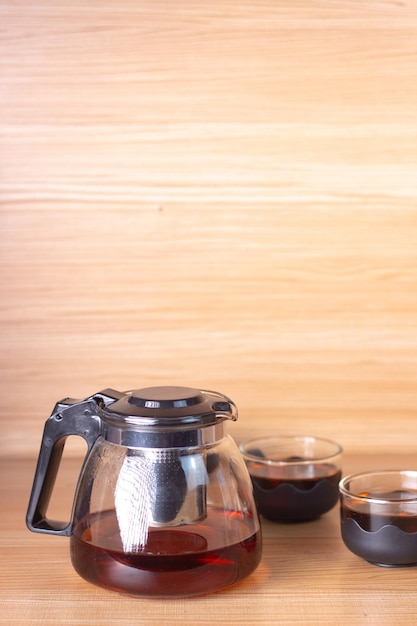 Glass teapot with tea on wooden background