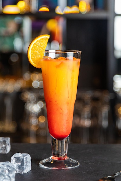 A glass of tequila sunrise cocktail and red tequila sunrise\
with a cherry tequila sunrise