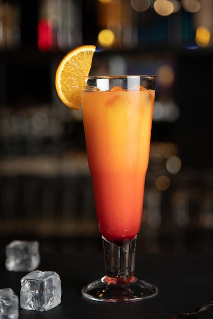 A glass of tequila sunrise cocktail and red tequila sunrise\
with a cherry tequila sunrise