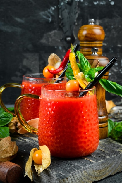 Photo glass of tomato alcoholic cocktail with spices and basil on a dark stone table