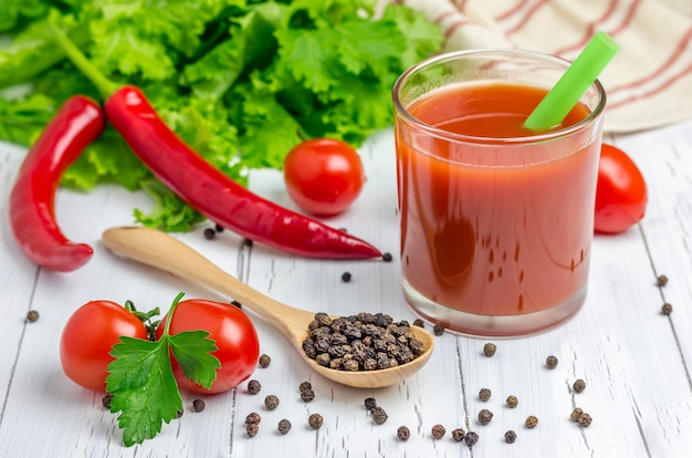 Glass of tomato juice with vegetables on background