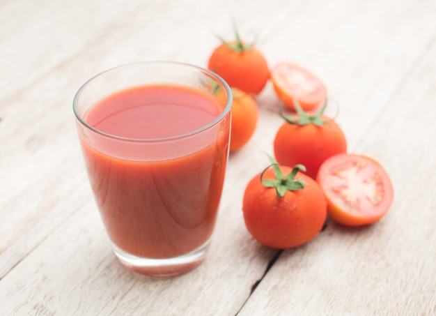Glass of tomato juice on wooden table