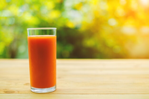 A glass of tomato juice on wooden table