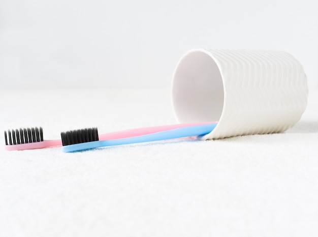 a glass for toothbrushes and two toothbrushes that lie on a towel