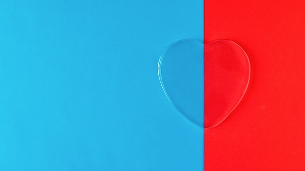 Glass transparent heart on red and blue background