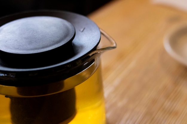 Glass transparent teapot with tea on wooden table