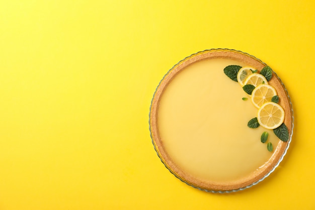 Glass tray with lemon tart on yellow, top view