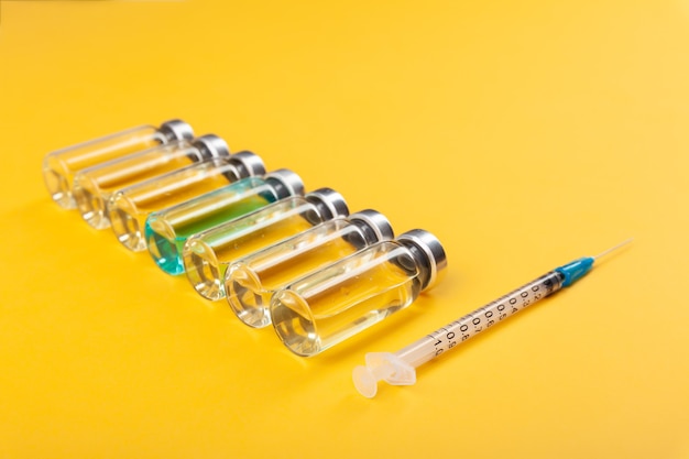 사진 유리 백신 앰플 병 및 노란색 배경에 주사기