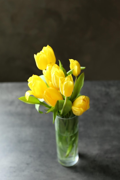 Glass vase with bouquet of beautiful tulips on color background