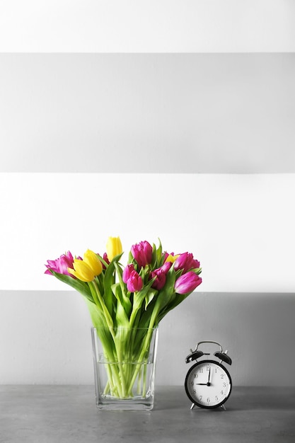色の背景に美しいチューリップの花束とガラスの花瓶