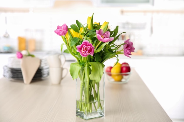 Glass vase with bouquet of beautiful tulips on table