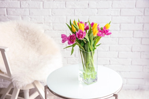 Glass vase with bouquet of beautiful tulips on table