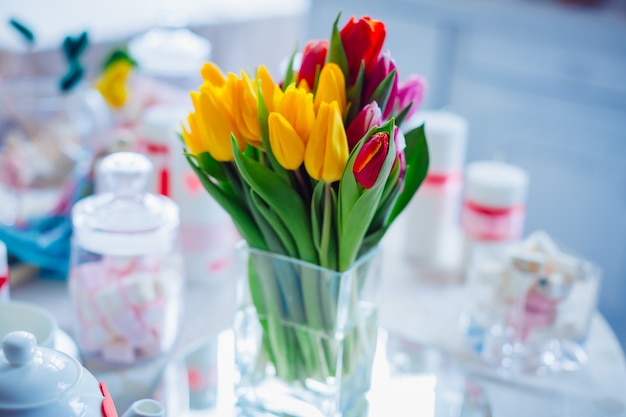 Vaso di vetro con bouquet di tulipani rossi, gialli e rosa