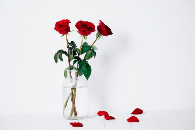 Glass vase with three red roses isolated on a white background