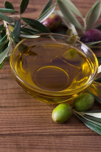 glass vessel with extra virgin olive oil and olives with branch